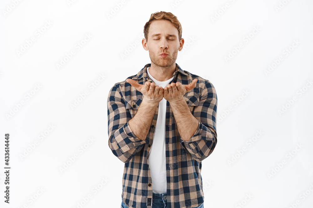 Passionate redhead man sending a kiss, blowing at open hands as blowing mwah at camera, standing romantic against white background Passionate redhead man sending a kiss, blowing at open hands as blowing mwah at camera, standing romantic against white background