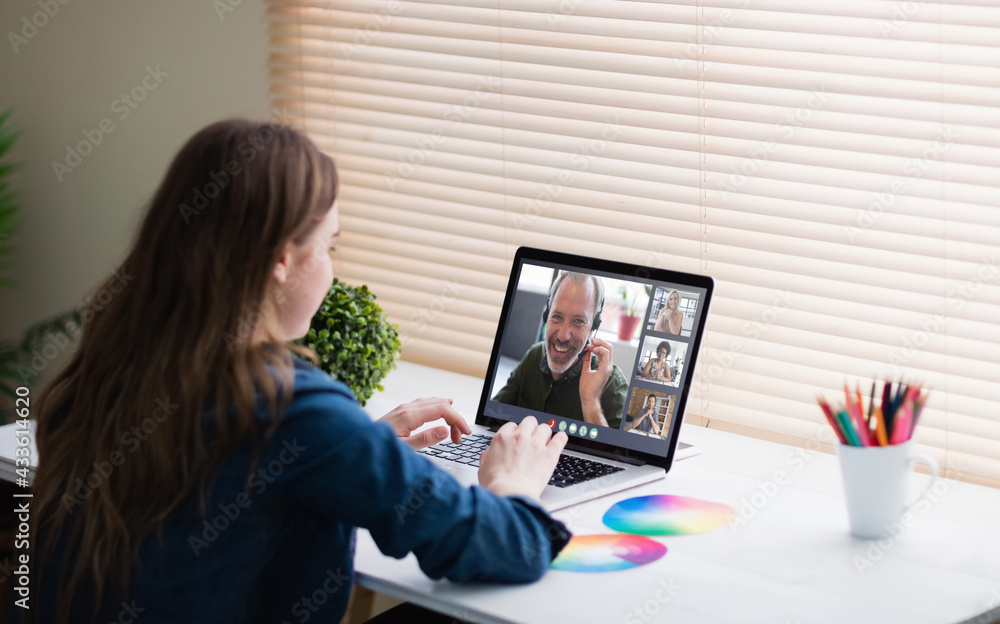 Caucasian businesswoman sitting at desk using laptop having video call with group of colleagues Caucasian businesswoman sitting at desk using laptop having video call with group of colleagues
