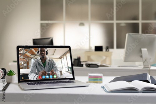African american man having video call on screen of laptop on desk