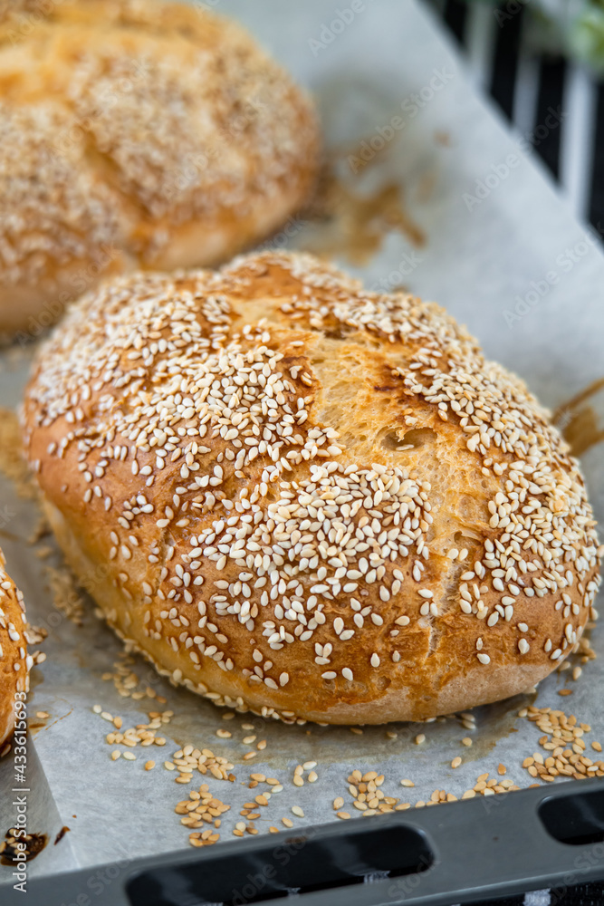 Fresh challah bread rolls hot from the oven on baking tray. Gluten free bread buns or mini loaves with sesame seeds and golden color ready to eat. Fluffy shaped bread, great for sandwiches. Side view