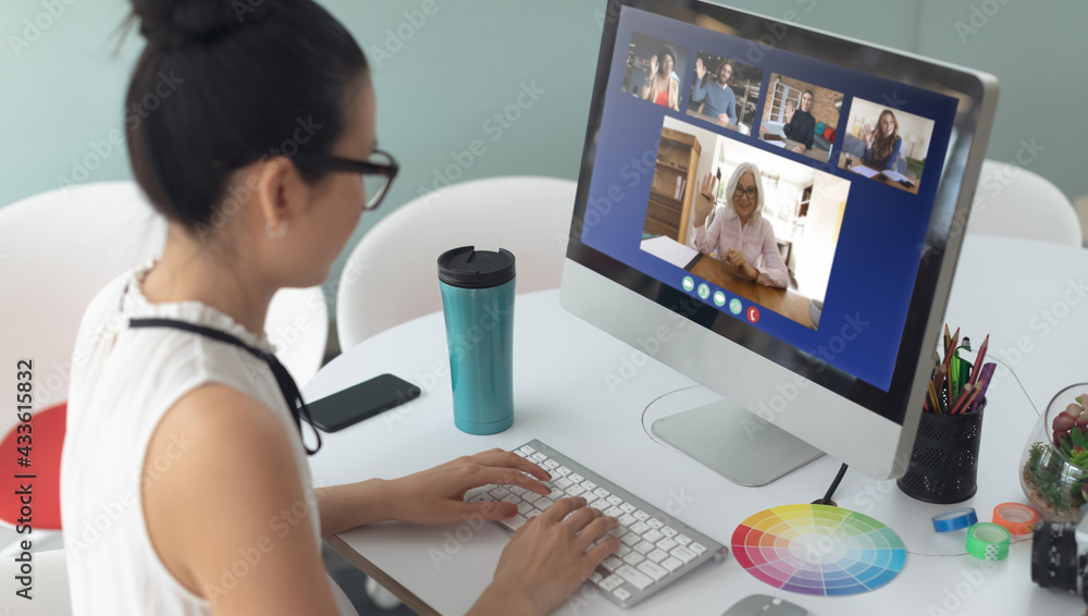 Asian woman sitting at desk having video call with coworkers Asian woman sitting at desk having video call with coworkers