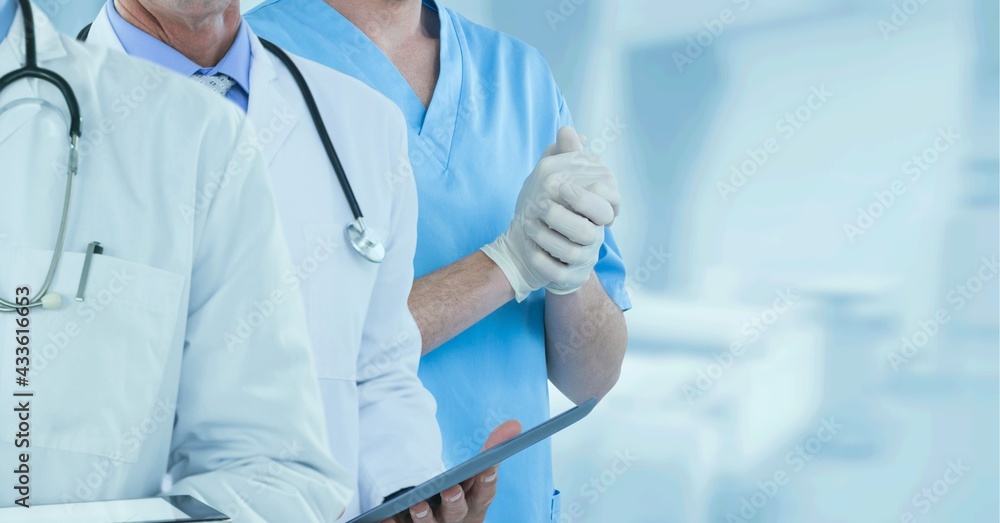 Mid section of team of medical professionals and health workers against hospital in background Mid section of team of medical professionals and health workers against hospital in background