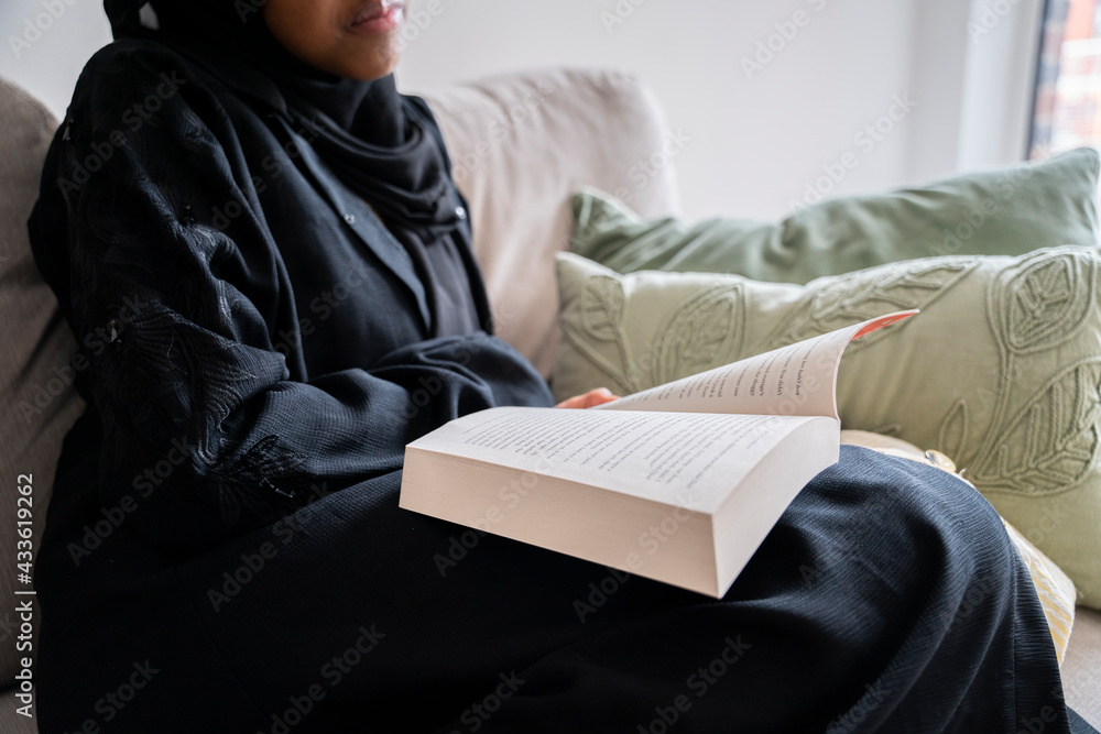 Black Muslim teenage girl reading a book in the living room Black Muslim teenage girl reading a book in the living room