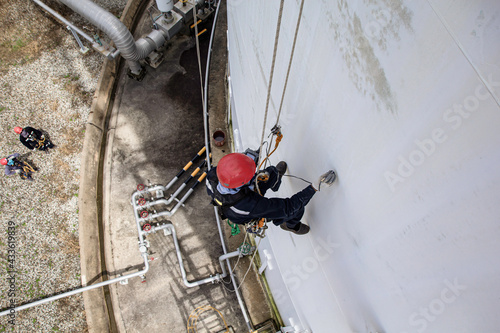 Male worker rope access height safety inspection of thickness storage oil and gas tank