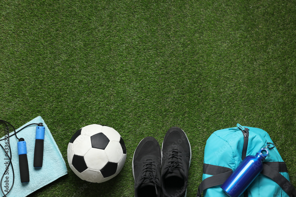 Obraz premium Flat lay composition with sports equipment on green grass, space for text