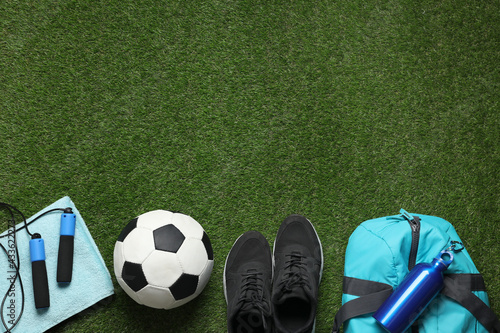 Flat lay composition with sports equipment on green grass, space for text