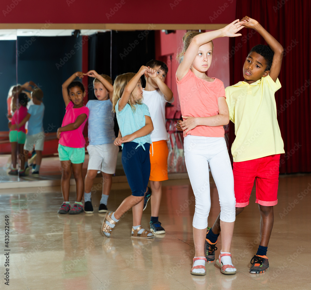 Group of joyful kids dancing salsa dance in modern studio