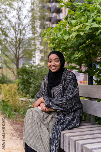 Black Muslim woman on a park bench
