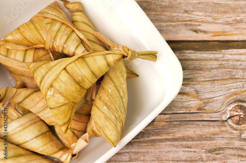 Ketipat palas or rice dumpling in a white plate. Ketupat palas is a natural rice casing made from young coconut leaves or cooking rice during Eid Mubarak or Eid Fitri