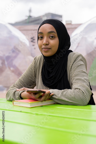 Black Muslim woman on a park bench 