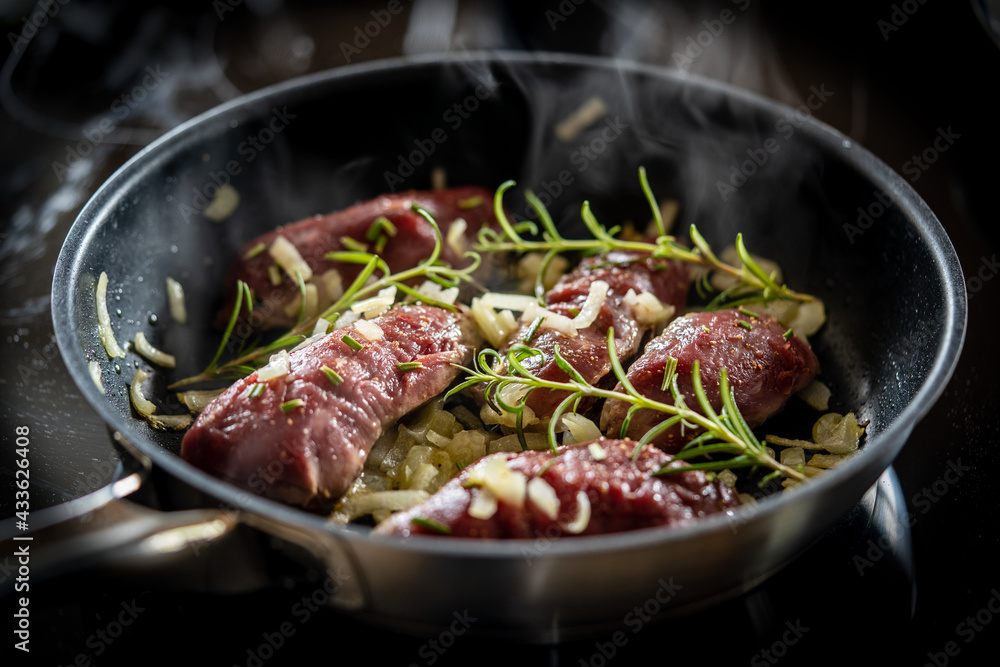 fresh cooking at home - raw meat from a red deer calf in a cooking pan with herbs, rosemary, onions , salt fresh cooking at home - raw meat from a red deer calf in a cooking pan with herbs, rosemary, onions , salt