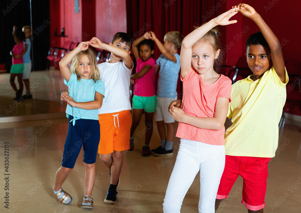 Fototapeta premium Smiling happy cheerful positive children primary school trying dancing salsa dance in modern studio