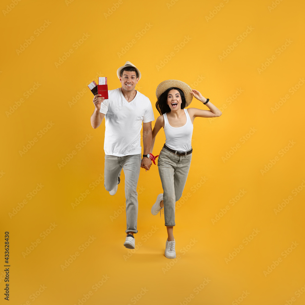 Couple of tourists with tickets and passports running on yellow background Couple of tourists with tickets and passports running on yellow background