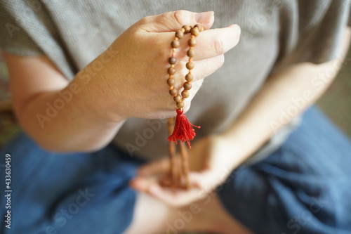 A  woman holding a mala yoga prayer bead necklace in her hand. photo