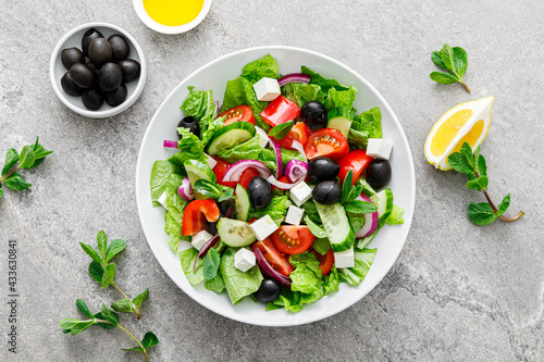 Fresh vegetable greek salad with lettuce, olives and feta cheese, top view