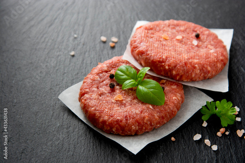 Raw red meat cotlets, cooking burgers. Minced red meat on black board.