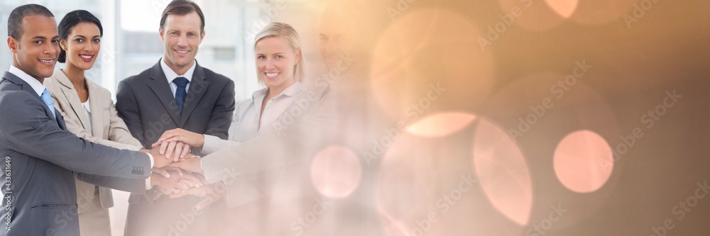 Composition of smiling business people stacking hands with spots of light Composition of smiling business people stacking hands with spots of light