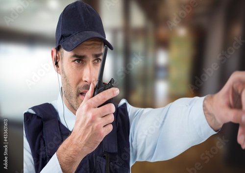 Composition of male security guard using walkie talkie holding hand out over blurred background photo