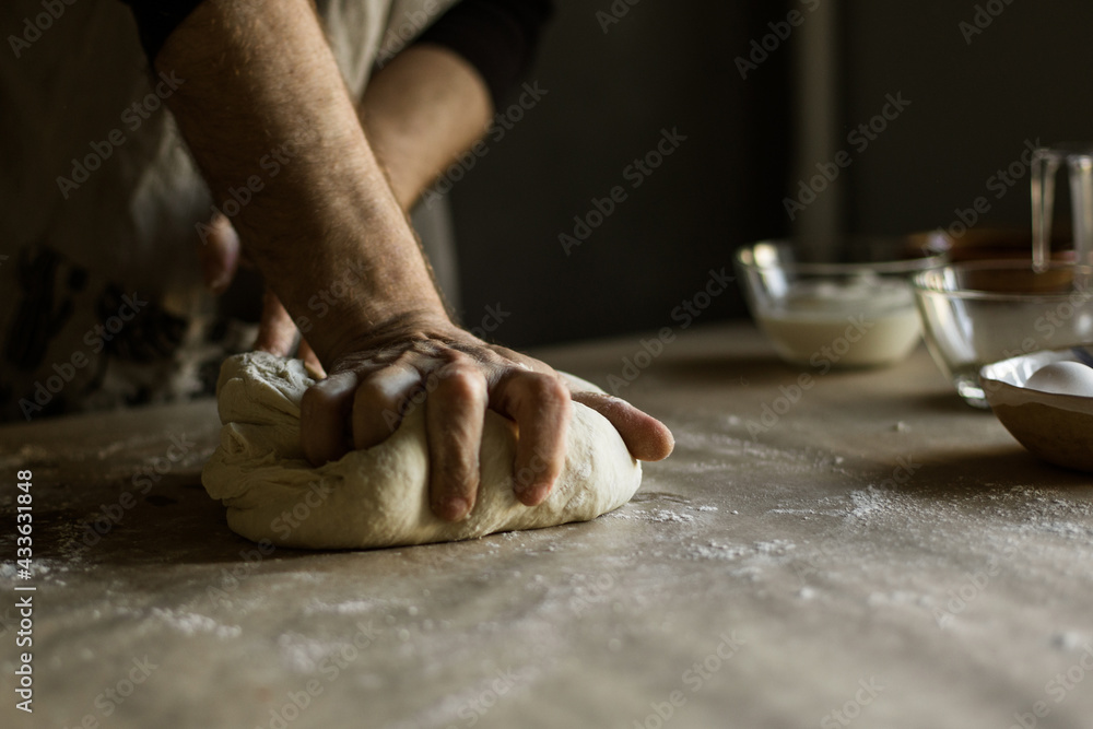 Male hands kneading dough on the table