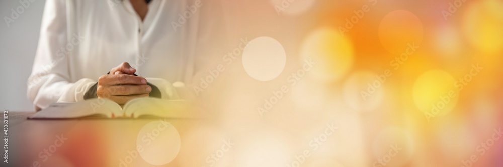 Composition of midsection of woman praying with holy bible with glowing spots of light Composition of midsection of woman praying with holy bible with glowing spots of light