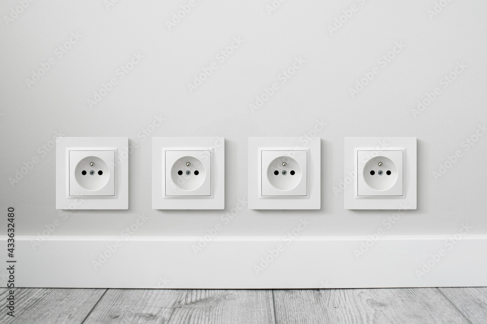 New electrical socket isolated on gray wall. Renovated studio apartment power supply background. Gray wooden floor. Empty copy space white plastic power outlet. Four sockets in a row. New electrical socket isolated on gray wall. Renovated studio apartment power supply background. Gray wooden floor. Empty copy space white plastic power outlet. Four sockets in a row.