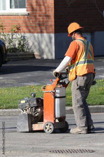 Worker cutting through pavement to expose utility lines for construction project
