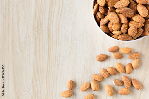 Almond nuts in white bowl with a wooden spoon on wooden background, selective focus.top view,top-down,flat lay.