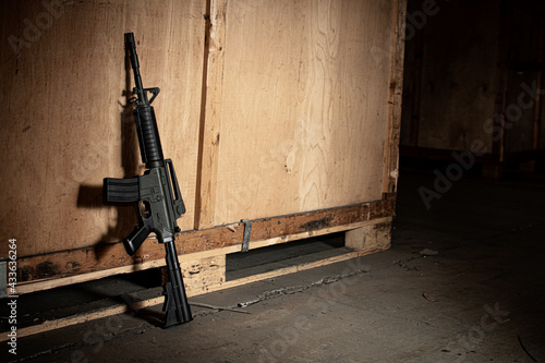 M4 carbine machine gun leant up against a wooden crate with dramatic lighting and shallow depth of field  photo