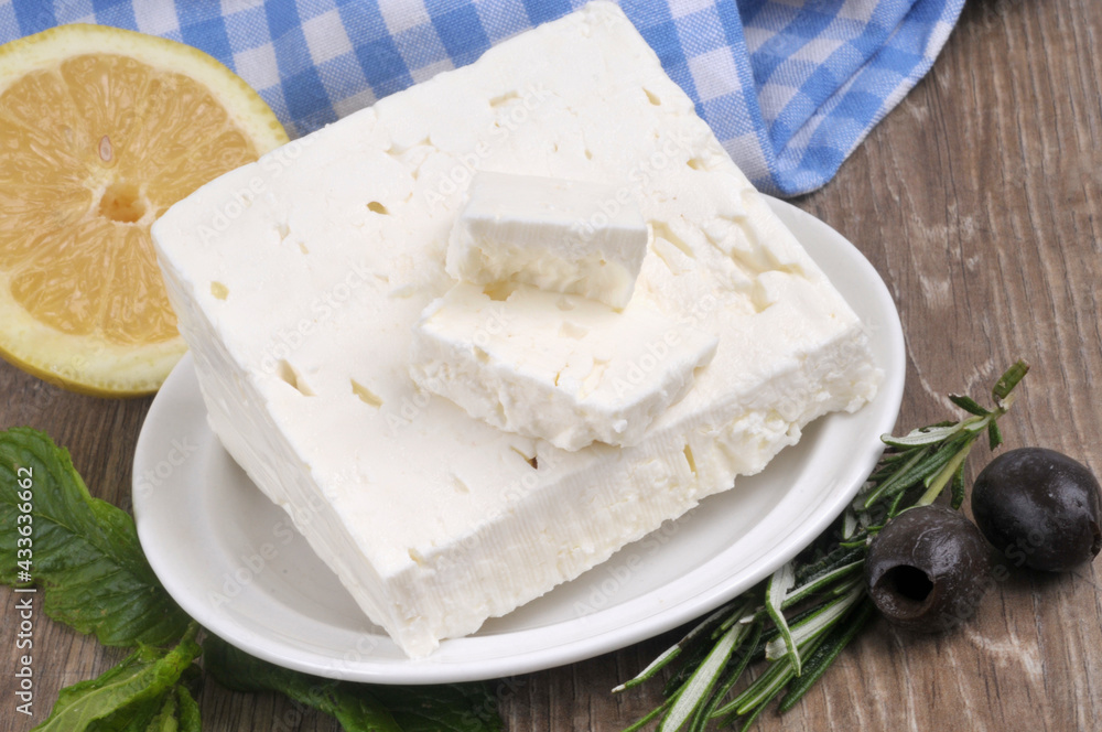 Morceau de feta dans une soucoupe avec du romarin, du citron, des olives noires et des feuilles de menthe Morceau de feta dans une soucoupe avec du romarin, du citron, des olives noires et des feuilles de menthe