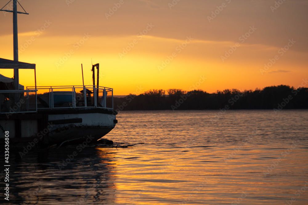 Fototapeta premium Ship on sunset, bright orange sun, big river