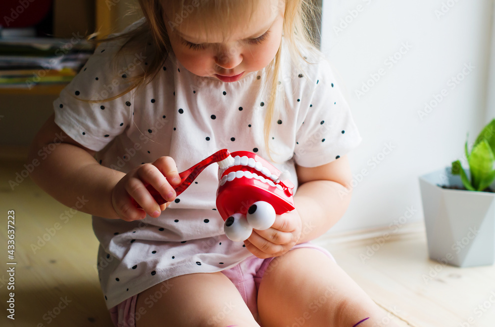 Little girl playing with dental jaw toy. Toddler brushing comic fake teeth, showing on a jaw