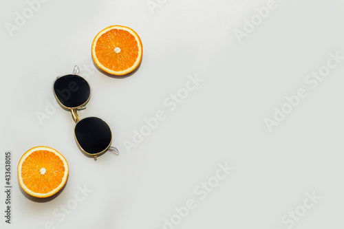 Oranges with sunglasses on a gray background. Citrus summer.
