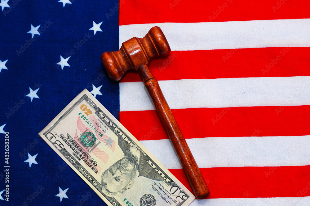 Judge gavel with money on the background of the USA flag.