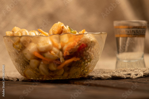 Pickled mushrooms in a glass dish and a mug of beer on a table covered with a homespun cloth with a rough texture.