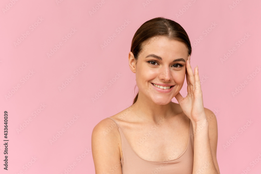Toothy smiling young woman with shiny glowing perfect facial skin and bare shoulder looking to camera Toothy smiling young woman with shiny glowing perfect facial skin and bare shoulder looking to camera