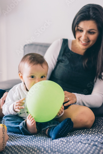 mum sitting couch at home playing male newborn photo