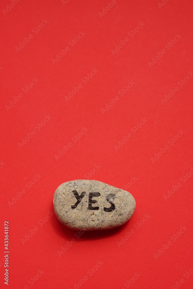 Pebble stone with text yes on it. Red background Pebble stone with text yes on it. Red background
