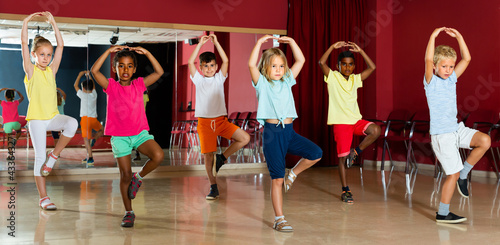 Fototapeta Naklejka Na Ścianę i Meble -  Cheerful little boys and beautiful girls having dancing class and hands up in class