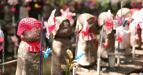 A slow motion of moving colorful windmills with Jizo statue daytime closeup photo