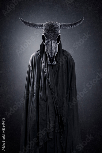 Foto Creepy figure with animal skull with horns in the dark