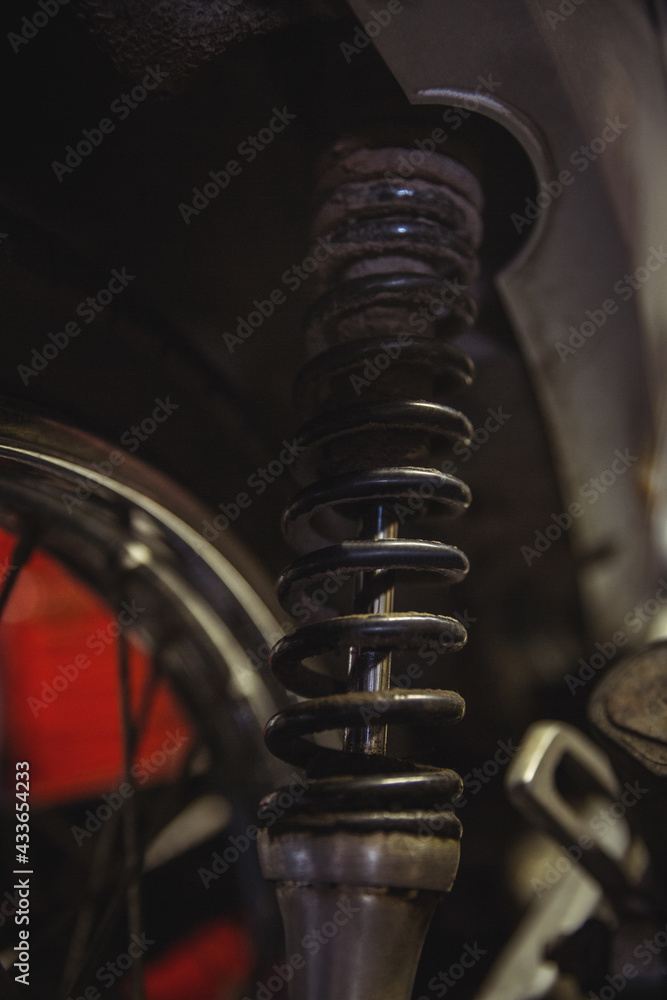 Close up of motorcycle wheel and shock absorber, standing in rapair workshop Close up of motorcycle wheel and shock absorber, standing in rapair workshop