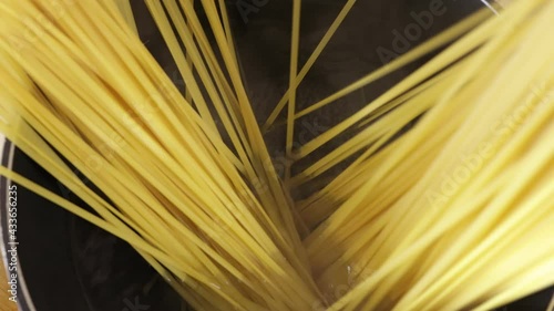 Top view of a pot of boiling water on the kitchen stove. The chef adds real Italian pasta. Home cooking of Italian pasta