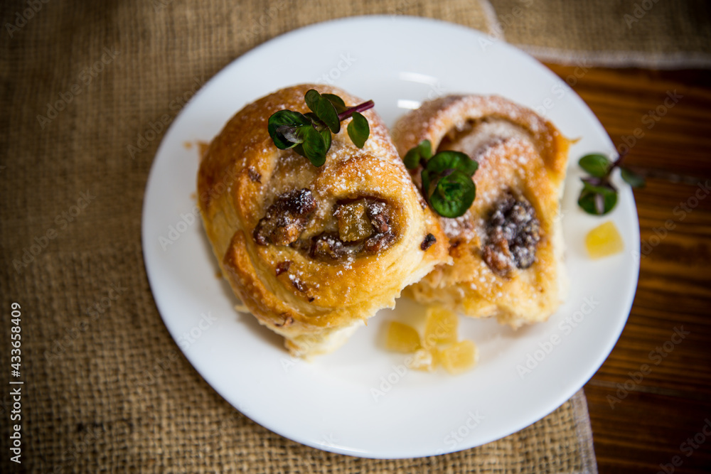 Sweet curled bun with jam, raisins in powdered sugar