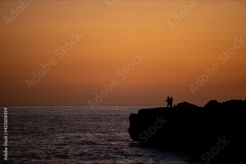 Sunrise golden sky silhouette view of people fishing