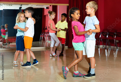 Group of happy positive childrens trying dancing with partner in classroom