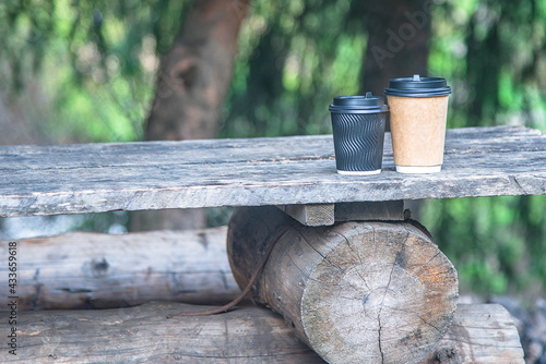 Close-up couple paper cups of coffee on natural outside background on the wooden table. For a coffee shop