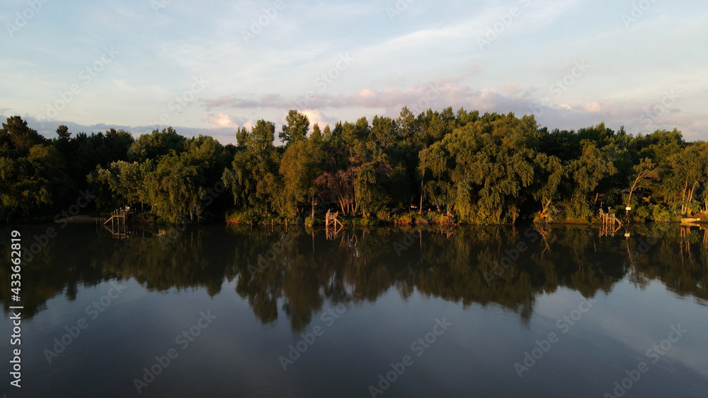 Amazon River with trees and pier on the shore, reflected on water Amazon River with trees and pier on the shore, reflected on water