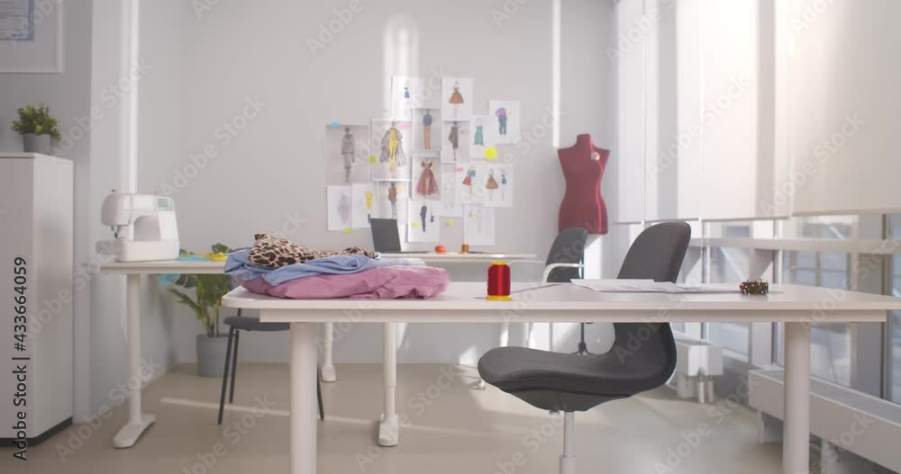 Empty fashion design studio with clothes, sewing machine and various sketches Empty fashion design studio with clothes, sewing machine and various sketches