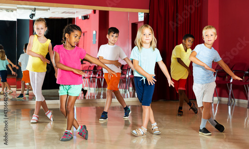 Positive children studying modern style dance in class indoors