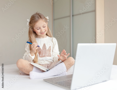 Caucasian girl learning online with laptop at home. Happy child doing homework at online school classes. Online education concept.